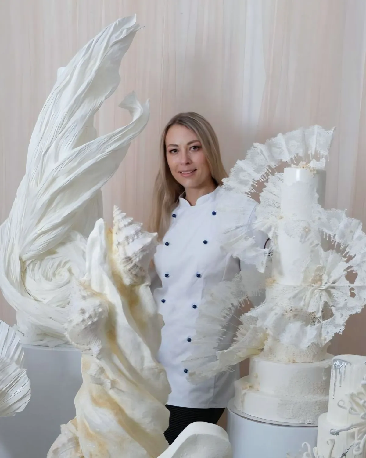 Viktoria Fink in Kochjacke zwischen ihren weißen Skulpturtorten